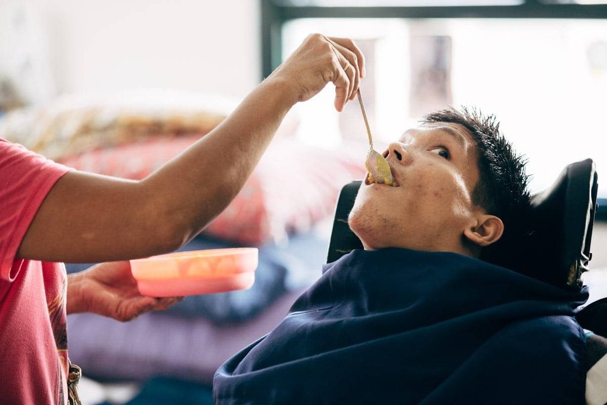 Woman feeding disabled man.