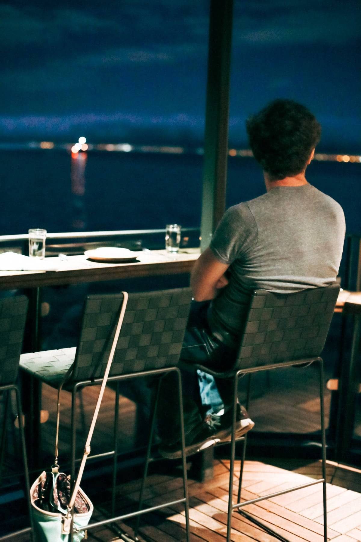 Man sitting in a chair looking out at the water.