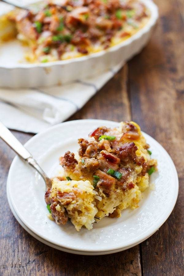 One piece of Ham and Sausage Hash Brown Egg Bake on a white plate with a fork.