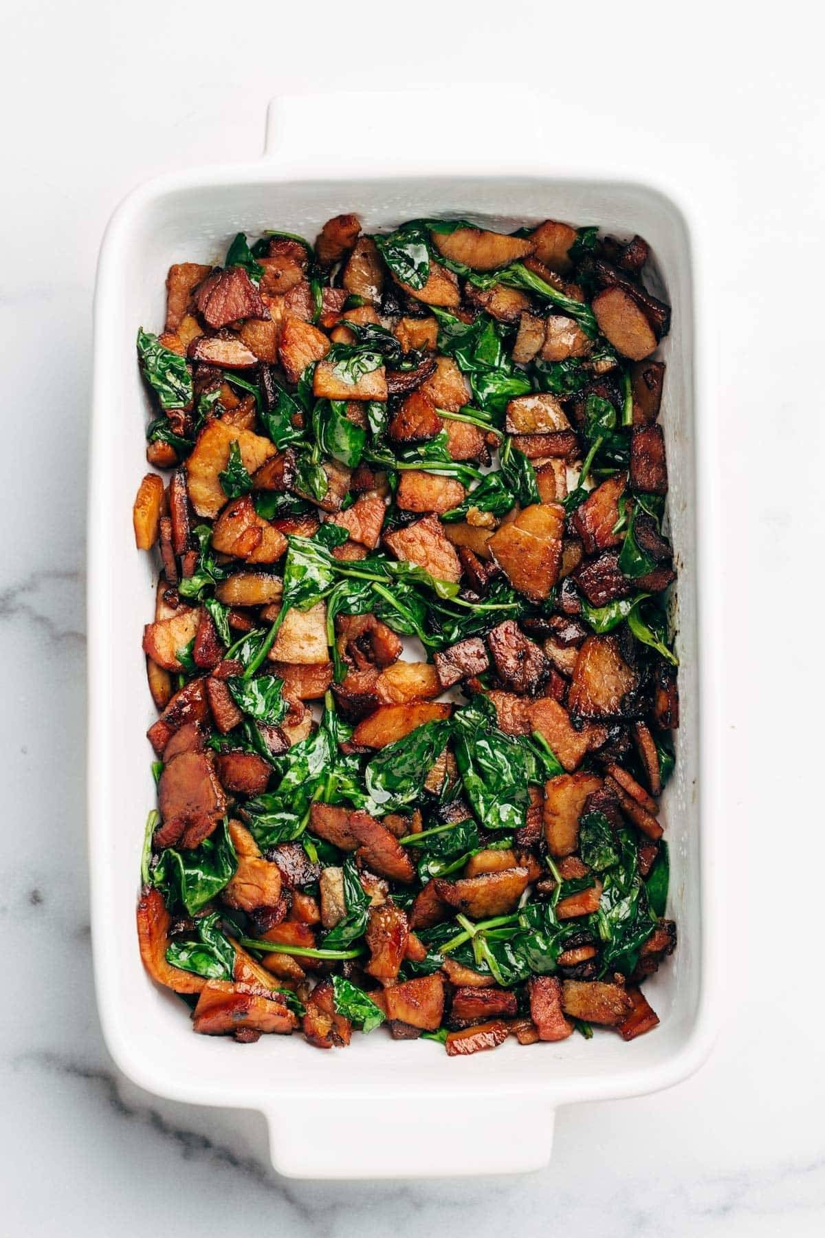 Onions, ham, and spinach in a casserole dish.