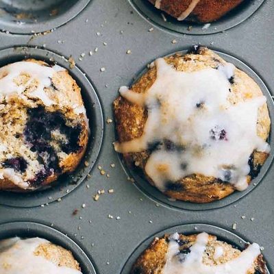 Whole Wheat Blueberry Muffins in a muffin tin with glaze.