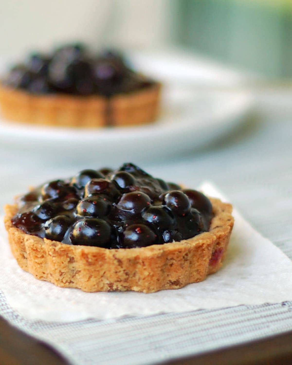 Two blueberry tarts with homemade crust and are packed full of fresh blueberry filling.